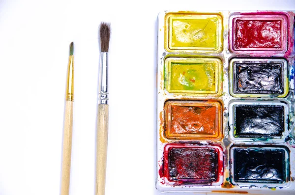 Palette with watercolors and brushes for paints on a white background. Watercolor paints. Brushes. Top and front view