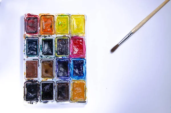 Palette with watercolors and brushes for paints on a white background. Watercolor paints. Brushes. Top and front view