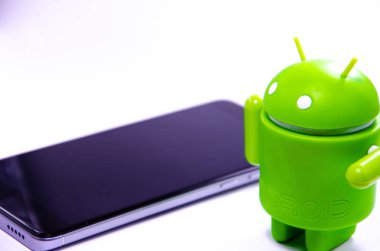 Nisan 2019. Los Angeles, Amerika Birleşik Devletleri. Beyaz bir arka plan ve bir akıllı telefon ile Yeşil plastik Android rakam. Şekil, logo Android, Google