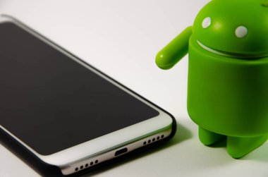 Mayıs 2019. Los Angeles, Amerika Birleşik Devletleri. Beyaz bir arka plan ve bir akıllı telefon ile Yeşil plastik Android rakam. Şekil, logo Android, Google