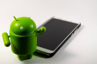 Mayıs 2019. Los Angeles, Amerika Birleşik Devletleri. Beyaz bir arka plan ve bir akıllı telefon ile Yeşil plastik Android rakam. Şekil, logo Android, Google