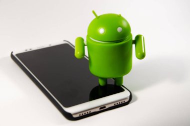 Mayıs 2019. Los Angeles, Amerika Birleşik Devletleri. Beyaz bir arka plan ve bir akıllı telefon ile Yeşil plastik Android rakam. Şekil, logo Android, Google