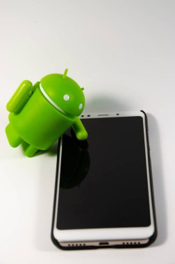 Mayıs 2019. Los Angeles, Amerika Birleşik Devletleri. Beyaz bir arka plan ve bir akıllı telefon ile Yeşil plastik Android rakam. Şekil, logo Android, Google