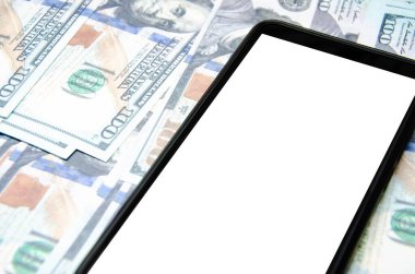 Dolar ve akıllı telefon. Çerçeveleri boyunca 100 dolarlık banknotlar uzanıyor üzerinde beyaz ekran ve açılı siyah bir akıllı telefon.