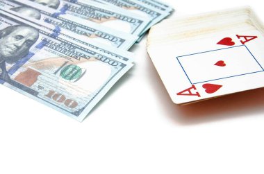 Dolar ve iskambil kağıtları. 100 dolarlık banknotlar beyaz bir arka planda bir yığın çiçeğin üzerinde duruyor. Üstünde bir deste kağıt, yukarıdan bir kupa ası ve bir açı var.