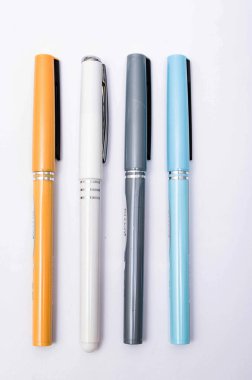 Dört adet mavi, beyaz, turuncu ve gri kalem yukarıdan, yandan, bir açıyla beyaz arka planda. Beyaz arka planda dört kalem yakın plan. Kalemden başlıklar