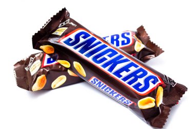 Haziran 2020. Kiev, Ukrayna. 50 gramlık iki küçük çubuk, beyaz arka planda bir haç şeklinde birbiri üzerine yatar. Makro olarak üst ve yan görünüm. Snickers çikolatası başka bir barda yatıyor..