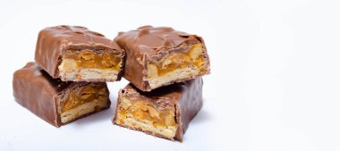 Makro paketlemeden 50 gram ağırlığında iki küçük snickers çubuğu yan yana uzanıyor ve makrodan ikiye bölünüyor. Snickers kesme ve makro. Karamel ve Fıstık