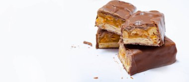 Makro paketlemeden 50 gram ağırlığında iki küçük snickers çubuğu yan yana uzanıyor ve makrodan ikiye bölünüyor. Snickers kesme ve makro. Karamel ve Fıstık