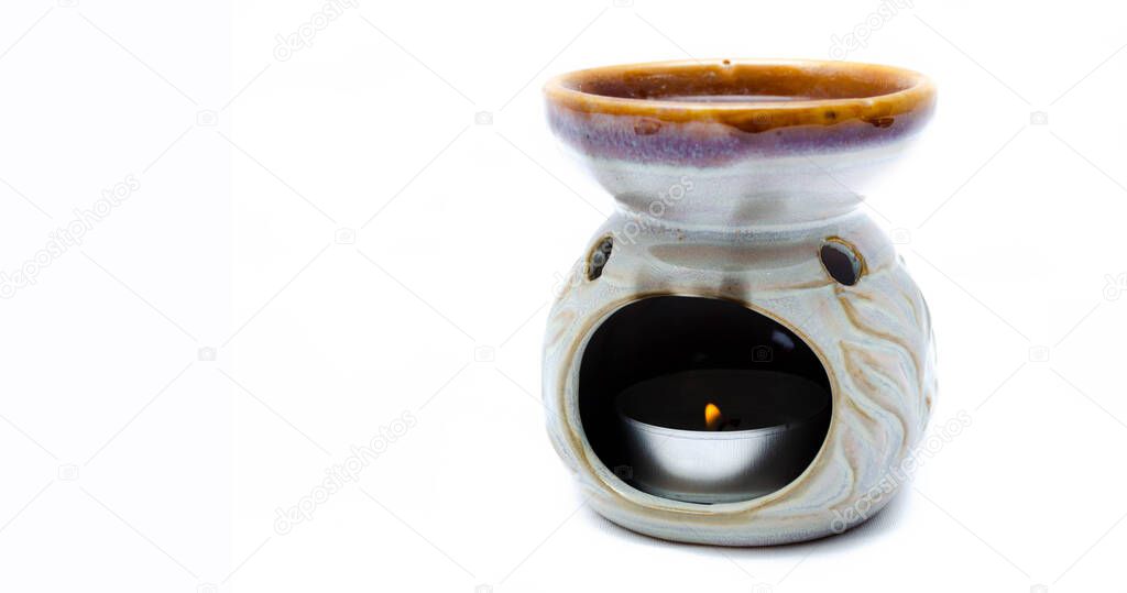 Aroma lamp on a white background.  Lamp with aromatic oils on a white background. A mans hand sets a candle in an aroma lamp