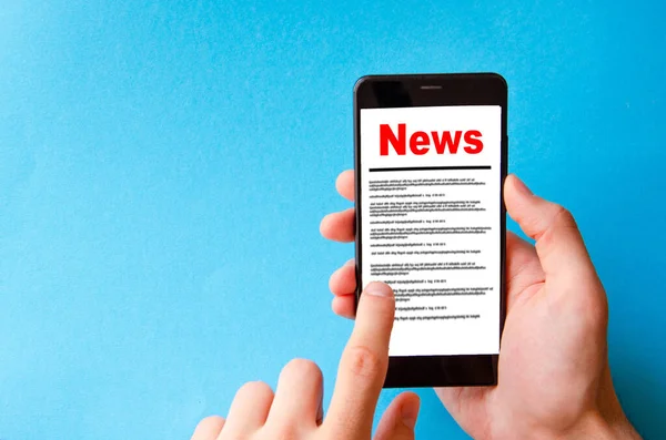 News. Reading the news. The inscription red news on the smartphone screen lies on a blue background. Male hand holds a smartphone, clicks, leafs through the news