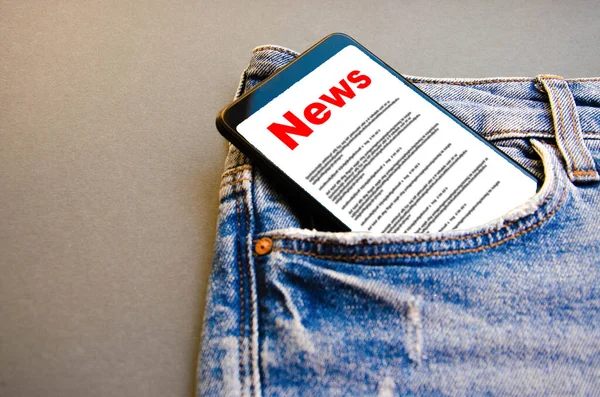 News. Reading the news. The inscription red news on the smartphone screen lies in a jeans pocket. A smartphone with a red inscription news sticks out of a jeans pocket on a black background