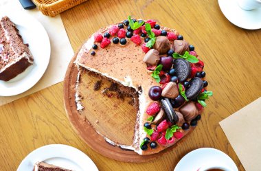 Yukardaki böğürtlenlerden kakaolu pasta, siyah frenk üzümü, bisküvi, yuvarlak tabakta tatlı. Pasta dilimi, makroda böğürtlen. İki numaralı doğum günü pastası. Üst manzara, yan manzara. Yakın plan.