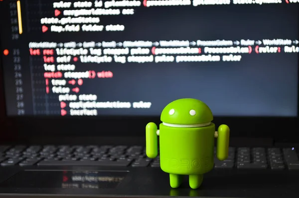 Yeşil bir android figürü programlama ekranında dizüstü bilgisayarın üzerinde duruyor. Büyüteçle bak. Temmuz 2020. Kiev, Ukrayna