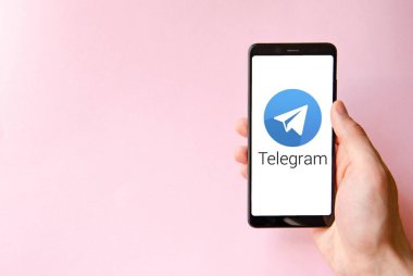 Telgraf var. Mavi, sarı, siyah arka planda bir telgraf akıllı telefonunun ekranında bir adamın elindeki akıllı telefon. Temmuz 2020. Kiev, Ukrayna.