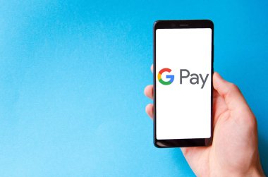 Google Pay. Google ödemeli akıllı telefon ekranında mavi, sarı, siyah arka planda erkek eli ile akıllı telefon. Temmuz 2020. Kiev, Ukrayna.