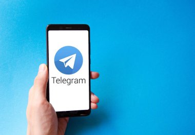 Telgraf var. Mavi, sarı, siyah arka planda bir telgraf akıllı telefonunun ekranında bir adamın elindeki akıllı telefon. Temmuz 2020. Kiev, Ukrayna.
