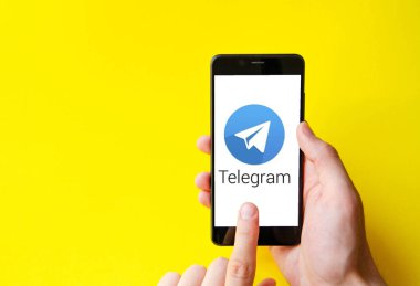 Telgraf var. Mavi, sarı, siyah arka planda bir telgraf akıllı telefonunun ekranında bir adamın elindeki akıllı telefon. Temmuz 2020. Kiev, Ukrayna.