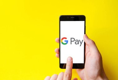 Google Pay. Google ödemeli akıllı telefon ekranında mavi, sarı, siyah arka planda erkek eli ile akıllı telefon. Temmuz 2020. Kiev, Ukrayna.