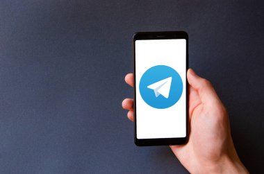 Telgraf var. Mavi, sarı, siyah arka planda bir telgraf akıllı telefonunun ekranında bir adamın elindeki akıllı telefon. Temmuz 2020. Kiev, Ukrayna.