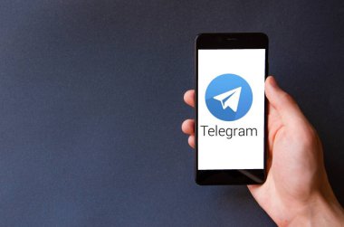 Telgraf var. Mavi, sarı, siyah arka planda bir telgraf akıllı telefonunun ekranında bir adamın elindeki akıllı telefon. Temmuz 2020. Kiev, Ukrayna.