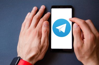 Telgraf var. Mavi, sarı, siyah arka planda bir telgraf akıllı telefonunun ekranında bir adamın elindeki akıllı telefon. Temmuz 2020. Kiev, Ukrayna.