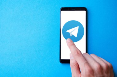 Telgraf var. Mavi, sarı, siyah arka planda bir telgraf akıllı telefonunun ekranında bir adamın elindeki akıllı telefon. Temmuz 2020. Kiev, Ukrayna.