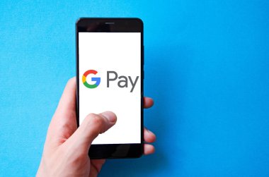Google Pay. Google ödemeli akıllı telefon ekranında mavi, sarı, siyah arka planda erkek eli ile akıllı telefon. Temmuz 2020. Kiev, Ukrayna.