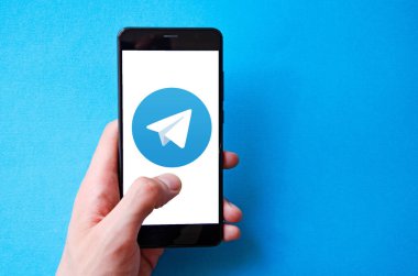 Telgraf var. Mavi, sarı, siyah arka planda bir telgraf akıllı telefonunun ekranında bir adamın elindeki akıllı telefon. Temmuz 2020. Kiev, Ukrayna.