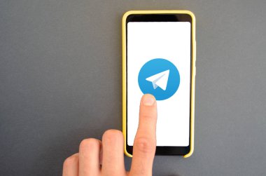 Telgraf var. Mavi, sarı, siyah arka planda bir telgraf akıllı telefonunun ekranında bir adamın elindeki akıllı telefon. Temmuz 2020. Kiev, Ukrayna.