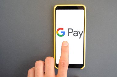 Google Pay. Google ödemeli akıllı telefon ekranında mavi, sarı, siyah arka planda erkek eli ile akıllı telefon. Temmuz 2020. Kiev, Ukrayna.