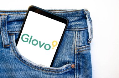 Glovo. Akıllı telefon ekranında Glovo yemek teslimatı. Beyaz ve sarı arka planda kot pantolon cebinde akıllı telefon. Temmuz 2020. Kiev, Ukrayna.