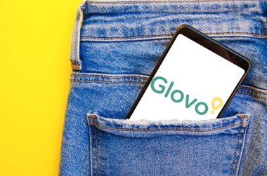 Glovo. Akıllı telefon ekranında Glovo yemek teslimatı. Beyaz ve sarı arka planda kot pantolon cebinde akıllı telefon. Temmuz 2020. Kiev, Ukrayna.