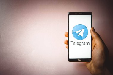 Telgraf var. Mavi, sarı, siyah arka planda bir telgraf akıllı telefonunun ekranında bir adamın elindeki akıllı telefon. Temmuz 2020. Kiev, Ukrayna.
