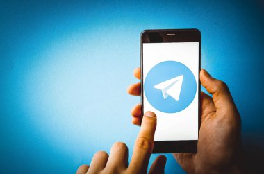 Telgraf var. Mavi, sarı, siyah arka planda bir telgraf akıllı telefonunun ekranında bir adamın elindeki akıllı telefon. Temmuz 2020. Kiev, Ukrayna.