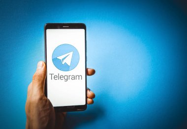 Telgraf var. Mavi, sarı, siyah arka planda bir telgraf akıllı telefonunun ekranında bir adamın elindeki akıllı telefon. Temmuz 2020. Kiev, Ukrayna.
