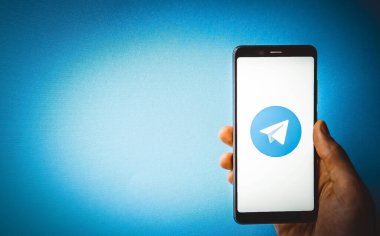 Telgraf var. Mavi, sarı, siyah arka planda bir telgraf akıllı telefonunun ekranında bir adamın elindeki akıllı telefon. Temmuz 2020. Kiev, Ukrayna.
