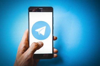 Telgraf var. Mavi, sarı, siyah arka planda bir telgraf akıllı telefonunun ekranında bir adamın elindeki akıllı telefon. Temmuz 2020. Kiev, Ukrayna.