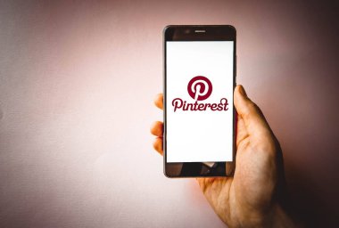 Pinterest. Mavi, sarı, siyah arka planda Pinterest akıllı telefon ekranında erkek eli ile akıllı telefon. Temmuz 2020. Kiev, Ukrayna.