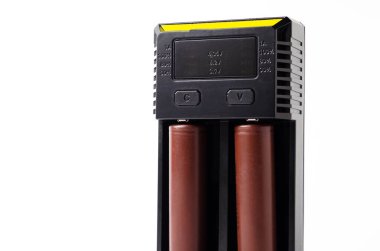 İki 18650 pil için siyah bir şarj aleti. Şarj olurken beyaz arka planda yeşil ve kahverengi bir batarya. Erkek eli pili şarj eder.