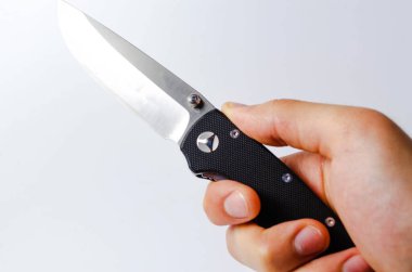 Beyaz arka planı siyah saplı katlanmış bir bıçak, açık ve kapalı. Bıçağın üzerinde paraşüt ipi var. Taktiksel katlama bıçağı yakın planda. Bir adamın elinde bıçak.