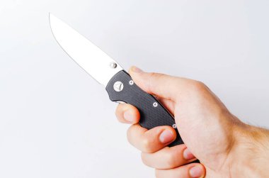 Beyaz arka planı siyah saplı katlanmış bir bıçak, açık ve kapalı. Bıçağın üzerinde paraşüt ipi var. Taktiksel katlama bıçağı yakın planda. Bir adamın elinde bıçak.