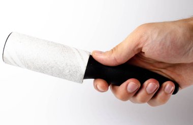 Beyaz arka planda giysileri yakın planda temizlemek için paten. Bir adamın elindeki giysileri temizlemek için esnek bir silindir. Kullanılmış, kirli çamaşır silindiri.