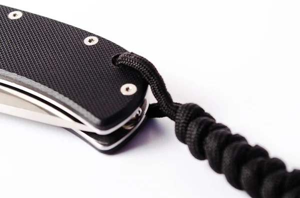 A folding knife with a black handle on a white background, open and closed. Paracord lanyard on the knife. Tactical folding knife in close-up