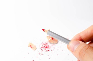 Beyaz arka planda kırmızı kalem talaşı var. Kalem ucu bütün ve beyaz bir arka planda kırılmış. Kalemden arta kalanlar. Macro, talaş yığını.