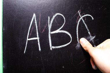 Okul yönetim kurulu. Alfabenin yazıldığı tahta, sayılar, bir toplama örneği. Tahtayı bir bezle sil. Okul yönetim kurulunun tebeşirli parmakları