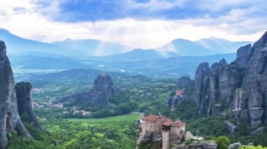 Rousanou rahibe manastırı ve St Nicholas Anapausas manastırı, Kastraki, Kalambaka, Thessaly, Yunanistan üzerinde, uzak güneş ışınları ve güzel bulutlar ile, gündüz meteora vadisinin görünümü - timelapse, tilt, zoom out
