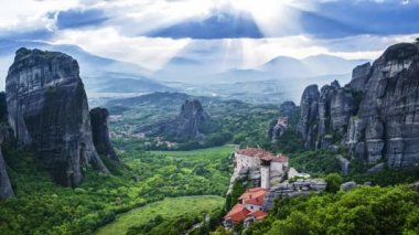 Gündüz Meteora vadisinin şaşırtıcı görünümü, kayalar arasında ve Rousanou rahibe manastırı ve St Nicholas Anapausas manastırı üzerinde çalışan ışınları, Kastraki, Kalambaka, Thessaly, Yunanistan - timelapse