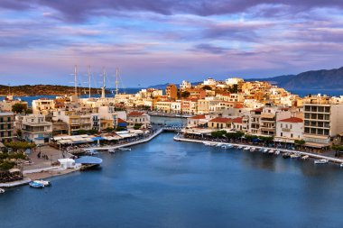 Yunanistan 'ın Girit adasındaki Voulismeni gölü ve Agios Nikolaos kasabasının gün batımında mavi gökyüzünde güzel bulutlarla renkli manzarası