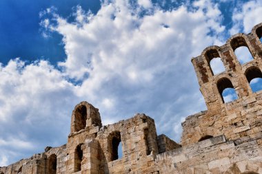Acropolis Hill, Atina, Yunanistan 'daki Herodes Atticus Tiyatrosu' nun parlak mavi gökyüzü ve süper bulutlardaki görüntüsü. Klasik antik Yunan tiyatrosu kalıntıları